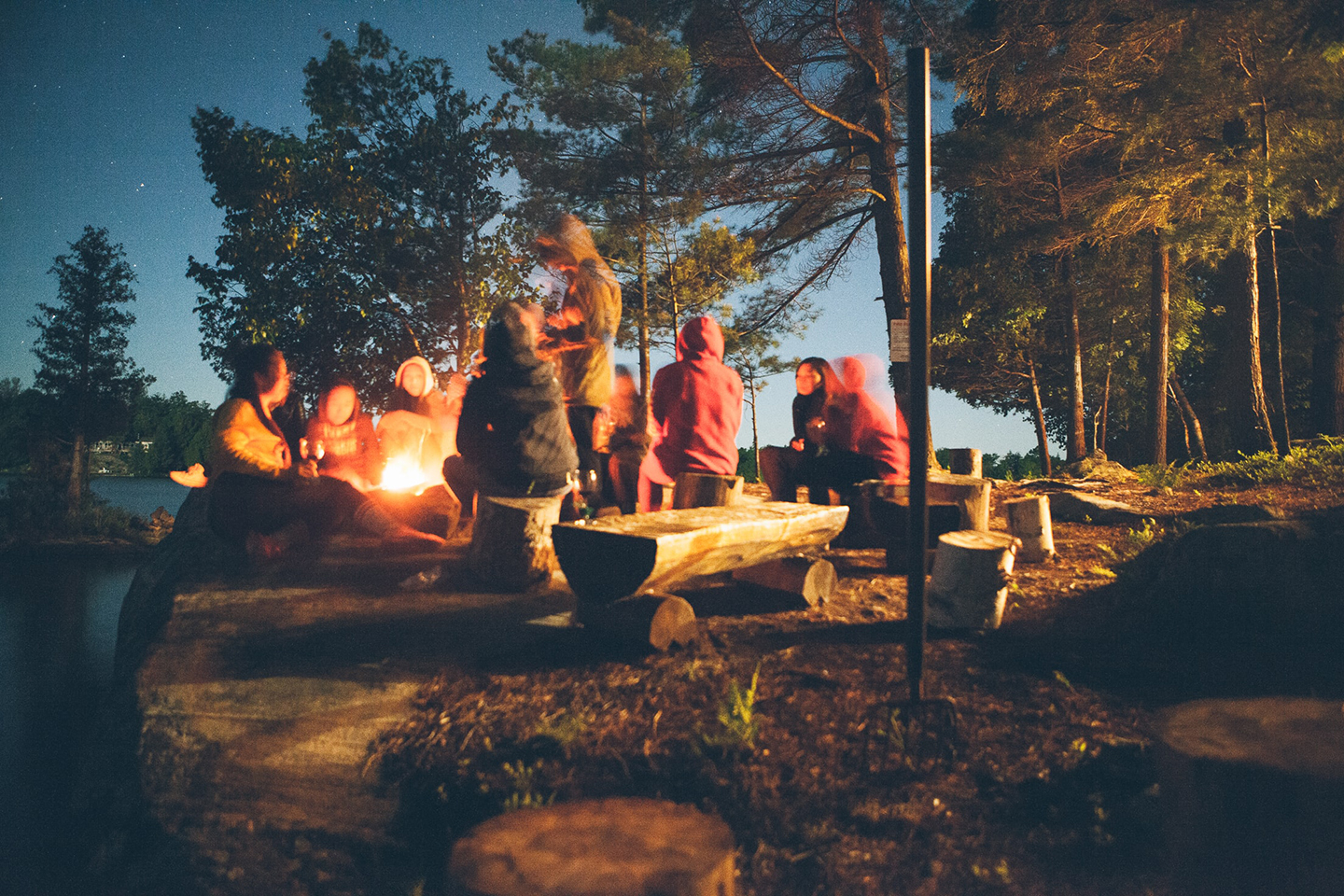 A group enjoys camping outside around a fire