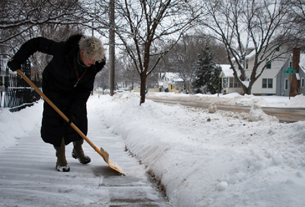 A woman shovels her sidewalk in the winter